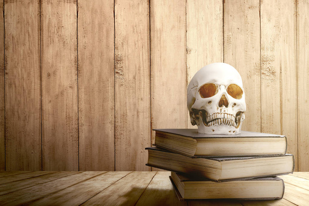 Pile of the book with a human skull on a wooden table - Foto, imagen