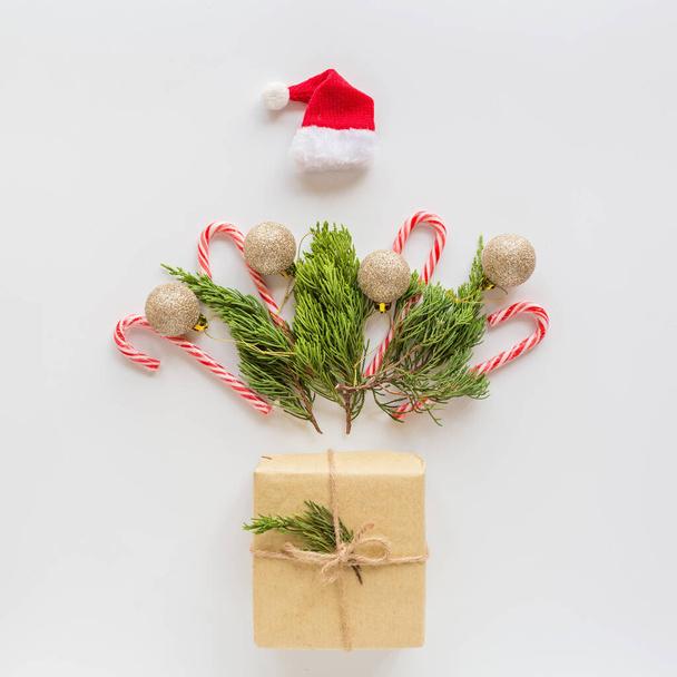 Christmas composition. Wrapped gift, fir branches, lollipop cane on white. new year concept. Greeting card, winter holidays, xmas celebration 2020. Flat lay, top view, copy space, mockup, template - Φωτογραφία, εικόνα
