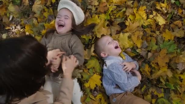Грайлива мама лоскоче щасливих маленьких дітей в парку
 - Кадри, відео