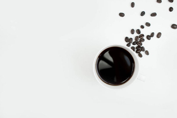 Черный кофе в белом стакане с кофейными зернами на белом спинке
 - Фото, изображение
