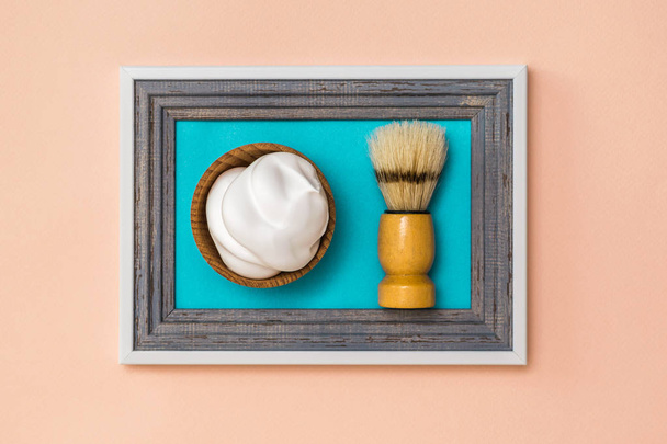 Scheerschuim scheren borstel en scheren in een frame op een koraal achtergrond. Minimalisme. Moderne creatieve creativiteit. - Foto, afbeelding
