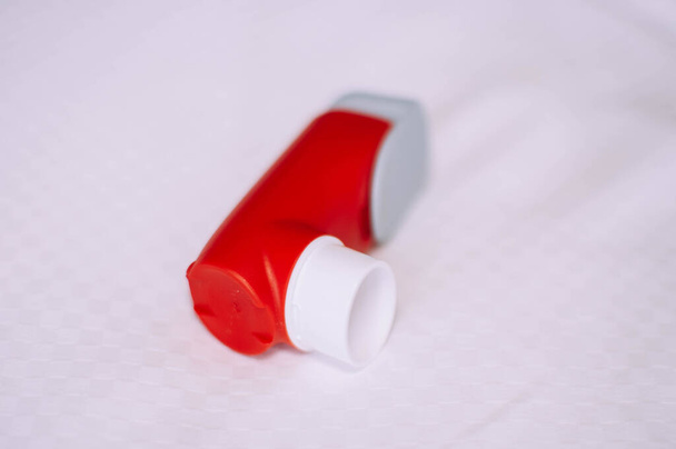 Un bodegón del inhalador de asma rojo y blanco se inventa sobre un fondo blanco
 - Foto, imagen