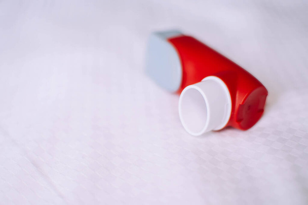 Un bodegón del inhalador de asma rojo y blanco se inventa sobre un fondo blanco
 - Foto, imagen