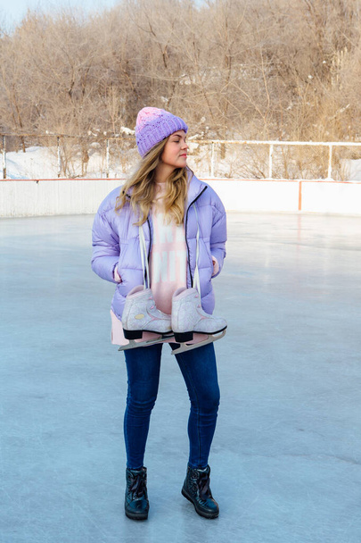 Lovely young woman with ice skates hanging on neck on the ice rink. - Φωτογραφία, εικόνα