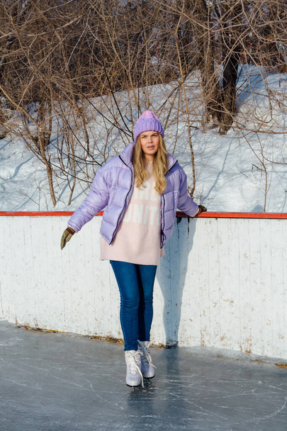 Lovely young woman with riding ice skates on the ice rink. - Foto, afbeelding