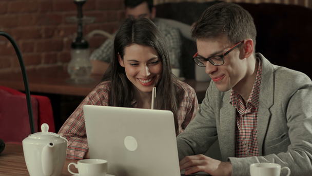 Young couple at cafe looking at laptop and smoking hookah - Filmagem, Vídeo