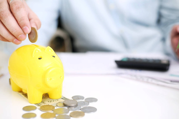  Zdjęcie osoby zdeponującej pieniądze w żółtej śwince. Odizolowane na tle. - Zdjęcie, obraz