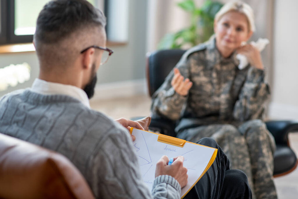 Psychologist making notes and writing during military rehabilitation - Фото, изображение