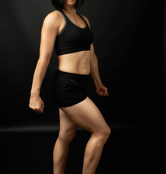 erwachsenes Mädchen mit sportlicher Figur in schwarzem BH und schwarzer Shorts - Foto, Bild