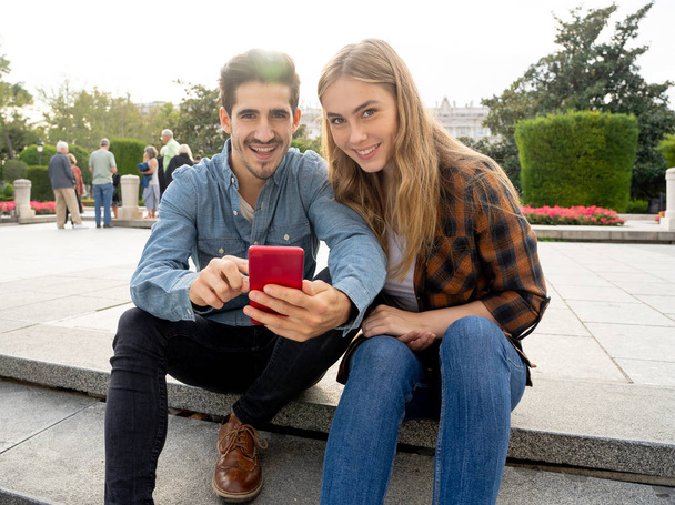 Young tourist couple consulting online travel guide blog or web on smart phone searching for locations and information on main landmarks while traveling around Europe. Travel industry and technology. - Φωτογραφία, εικόνα