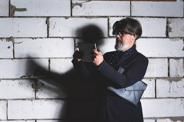 Mature man architect watching plan on his tablet about next project against the white wall - Fotoğraf, Görsel