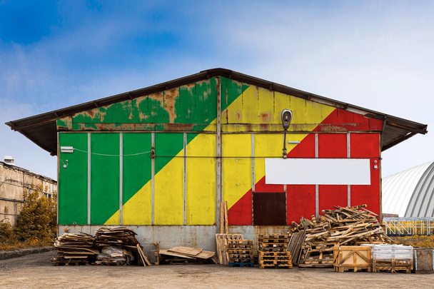 Nahaufnahme der Nationalflagge der Republik Kongo, die an einem Sommertag auf die Metallwand eines großen Lagerhauses das geschlossene Territorium gemalt hat. das Konzept der Lagerung von Gütern, der Eintritt in ein geschlossenes Gebiet, der Tourismus - Foto, Bild