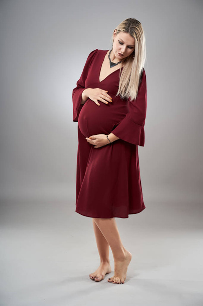 Studio full body portrait of a pregnant woman in red dress - Fotografie, Obrázek