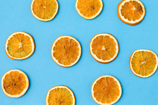 dried orange slices on blue background - Foto, afbeelding
