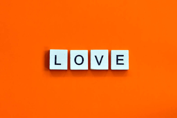 Domowej roboty drewniana płytka z literami na pomarańczowym tle, słowo miłość - Zdjęcie, obraz