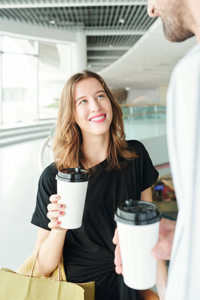 Mooie jonge blanke vrouw drinken take-out koffie met vriendje na het winkelen in winkelcentrum samen op zaterdag - Foto, afbeelding