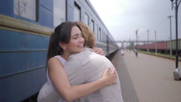 Гарна емоційна дівчина обіймає хлопця і сміється біля залізничної карети на станції "Поїзд" після розлучення. - Кадри, відео