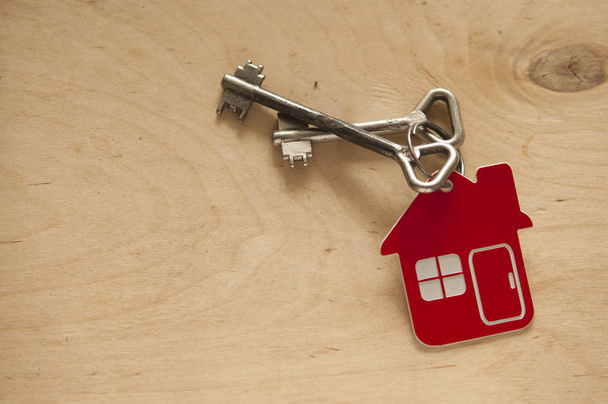 House key on a house shaped keychain on wooden background. Real  - Foto, Imagen