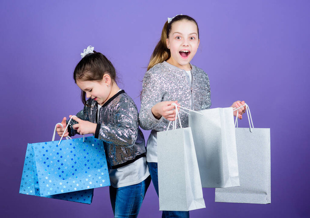 Black friday. Sale and discount. Shopping day. Children bunch packages. Kids fashion. Girls sisters friends with shopping bags violet background. Because image is everything. Shopping and purchase - Фото, зображення