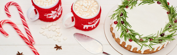 top view of christmas pie with rosemary, candy canes and two cups of cocoa with marshmallows on white wooden table    - Φωτογραφία, εικόνα