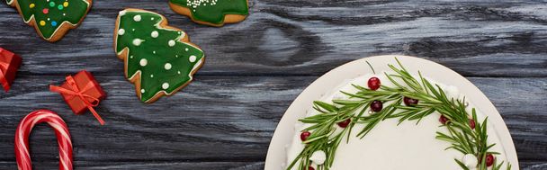 vista superior del pastel de Navidad, bastones de caramelo, regalos y galletas en la mesa de madera oscura
  - Foto, imagen