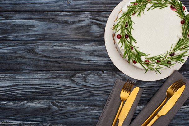 vista superior de pastel de Navidad con tenedores y cuchillos en servilletas en mesa de madera oscura
 - Foto, Imagen