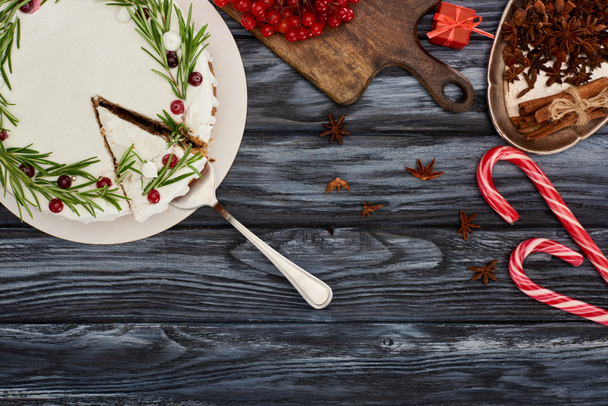 vista superior da torta de Natal com alecrim e cranberries na mesa de madeira escura com bengalas doces, bagas viburnum e sementes de anis estrelado
 - Foto, Imagem