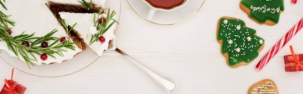 widok z góry ciasto świąteczne, filiżanka herbaty i ciasteczka choinkowe na białym drewnianym stole - Zdjęcie, obraz