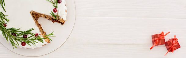 Biberiyeli noel pastası ve beyaz ahşap masadaki kızılcıklı küçük hediyeler. - Fotoğraf, Görsel