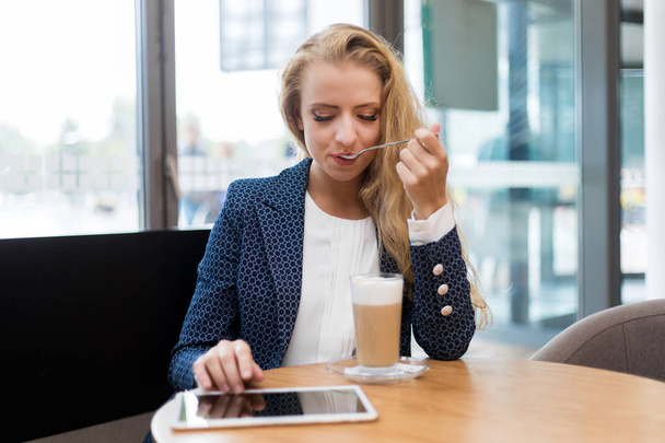 Young businesswoman on a coffee break. Using tablet computer. - Foto, imagen
