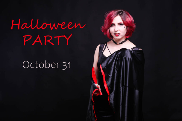 A girl with red hair, dressed in a mantle, on a black background. Halloween concept. - 写真・画像