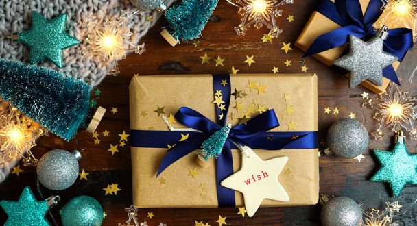 Wrapping Christmas holiday blue gifts on dark wood table, nightime flat lay. - Photo, Image