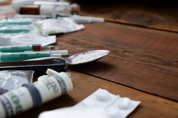 Mnoho omamných látek a zařízení pro přípravu drog leží na starém dřevěném stole - Fotografie, Obrázek