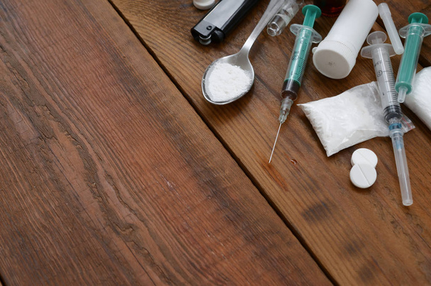 Um monte de substâncias narcóticas e dispositivos para a preparação de drogas estão em uma velha mesa de madeira
 - Foto, Imagem