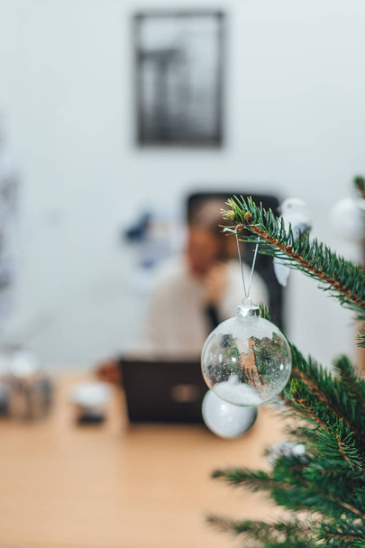 Árvore de Natal decorada no escritório, empresária em fundo borrão trabalhando no laptop
 - Foto, Imagem