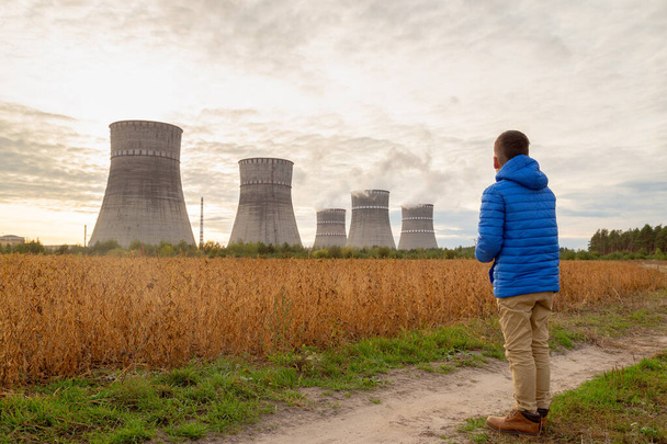 Boy looks at the nuclear power plant chimney pipes. Nuclear ener - Photo, Image