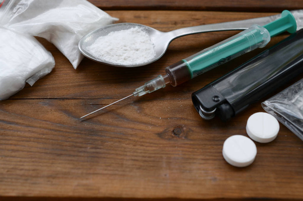 Veel verdovende middelen en hulpmiddelen voor de bereiding van drugs liggen op een oude houten tafel. - Foto, afbeelding