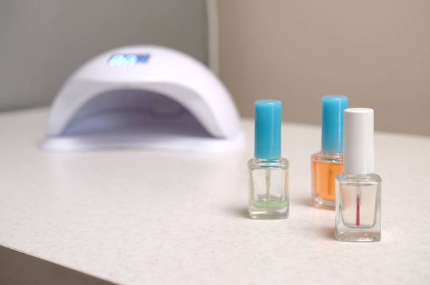 Lampada a diodi UV luci per unghie e set di smalto cosmetico per manicure e pedicure su sfondo bianco tavolo
 - Foto, immagini