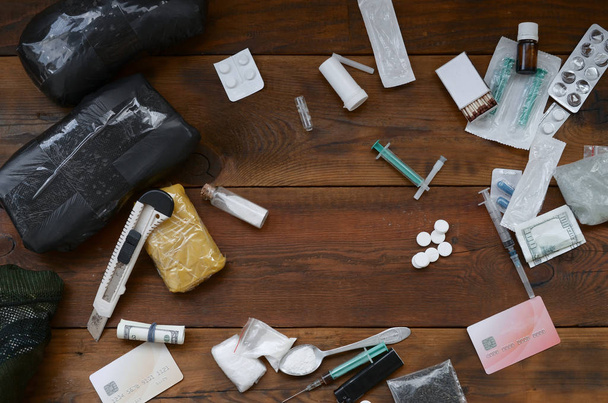 Пакети порошкових наркотиків, доларові банкноти та синтетичні таблетки медичний шприц
 - Фото, зображення