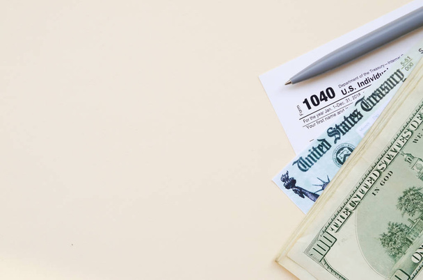 1040 Déclaration de revenus des particuliers avec chèque de remboursement et billets de cent dollars sur fond beige
 - Photo, image