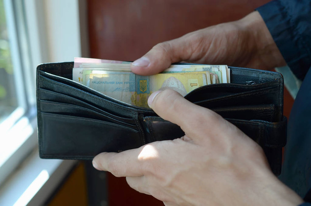Fechar as mãos masculinas abriu a carteira ou bolsa com moeda ucraniana hryvnia
 - Foto, Imagem