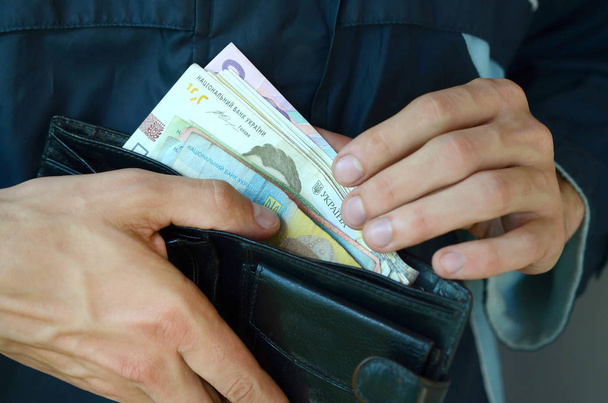Fermer les mains masculines ouvert le portefeuille ou sac à main avec de l'argent ukrainien monnaie hryvnia
 - Photo, image
