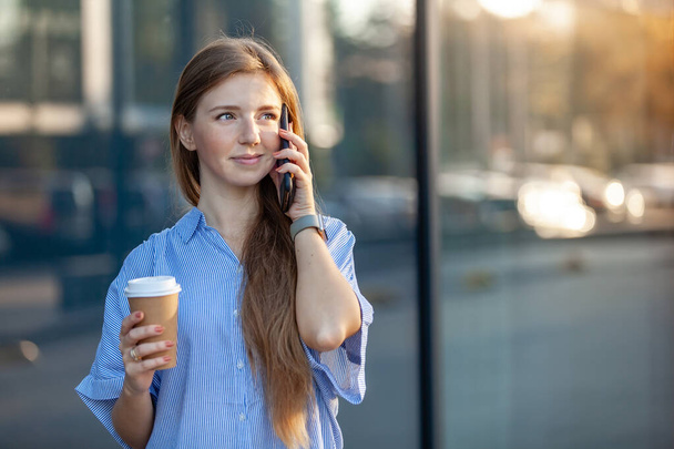 Happy attractive smiling woman, talking on cellphone, holding a coffee to go - Fotoğraf, Görsel