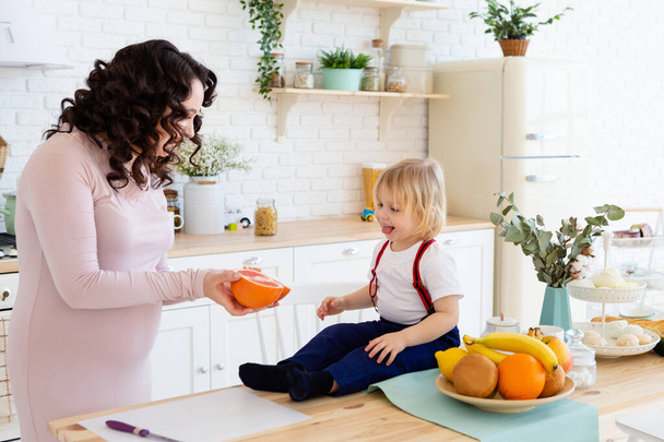 Moeder geeft haar zoon een sinaasappel. - Foto, afbeelding