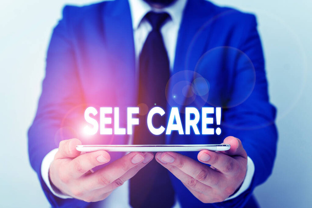 Handwriting text writing Self Care. Concept meaning practice of taking action to preserve or improve ones own health Businessman in blue suite with a tie holds lap top in hands. - Photo, Image