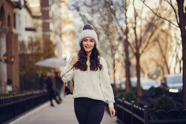 Cute brunette in a white sweater in a city - Φωτογραφία, εικόνα