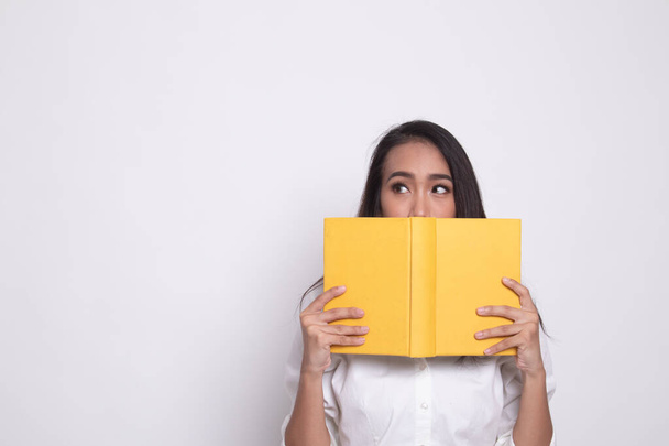 Fiatal ázsiai nő, egy könyv terjed ki az arcát. - Fotó, kép