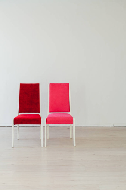 deux chaises rouge et rose se tiennent dans la chambre blanche
 - Photo, image