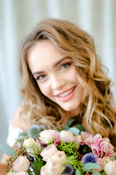 Close up portrait of young nice bride with bouquet at photo studio. - Fotó, kép