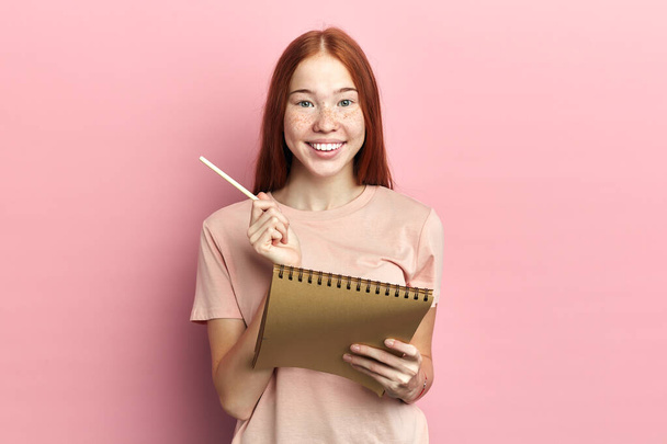 Close-up portrait of a beautiful positive excited woman making notes - Фото, изображение